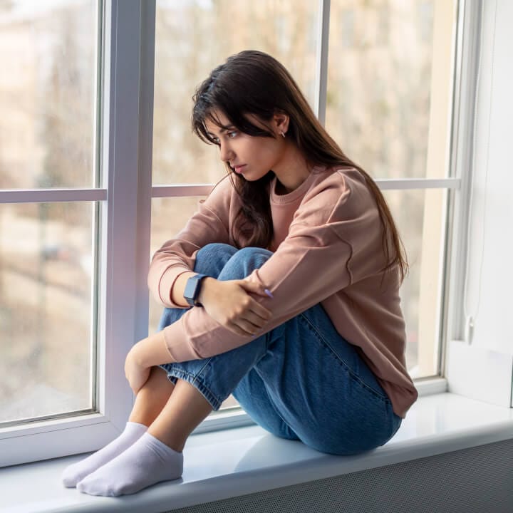 Sad woman looking out of window at home